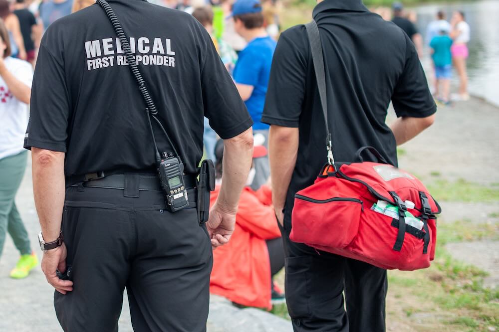 Medical first responders walking along a road wearing black uniforms
